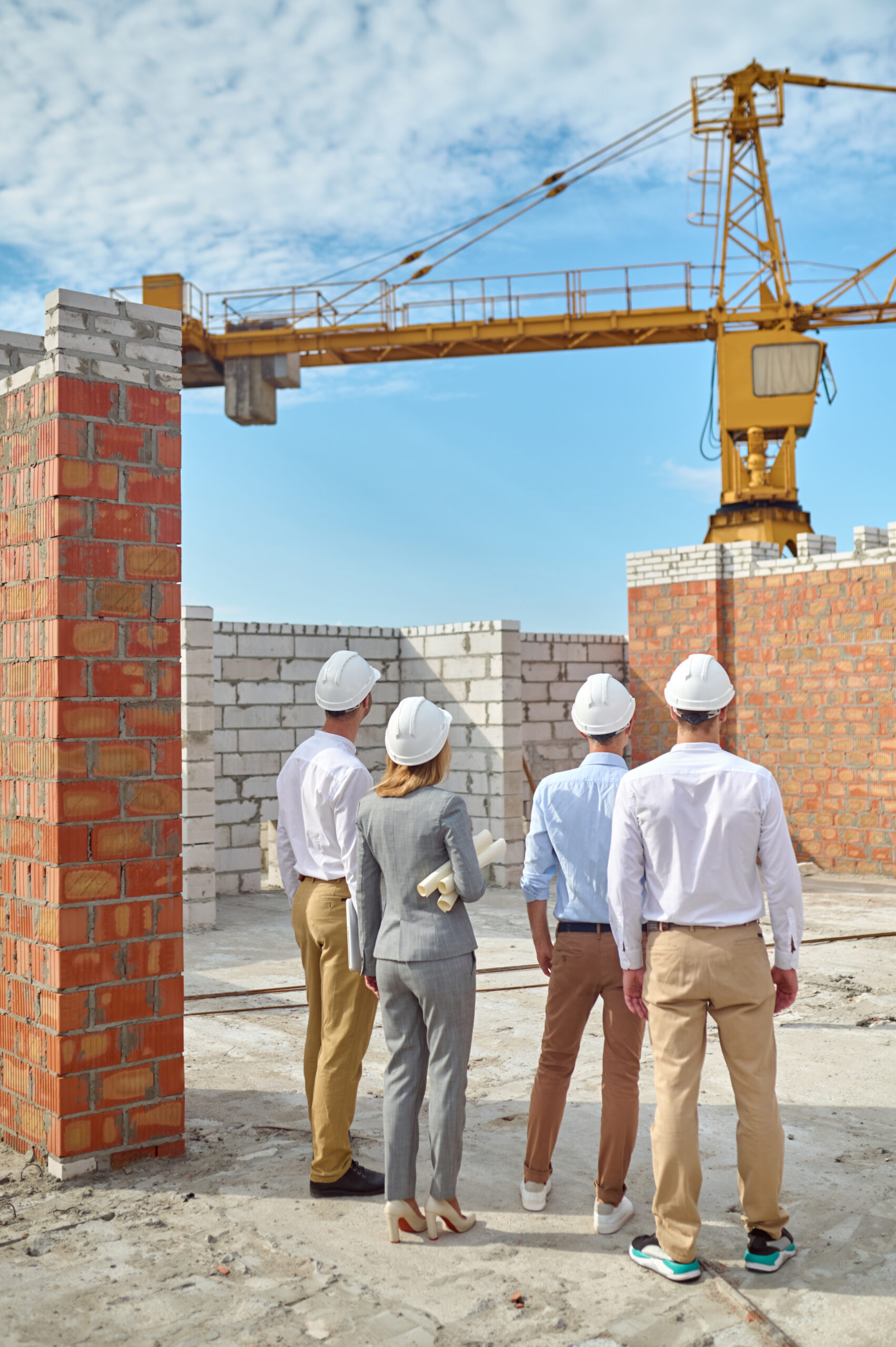 Equipo técnico supervisando una obra de construcción con grúa de fondo